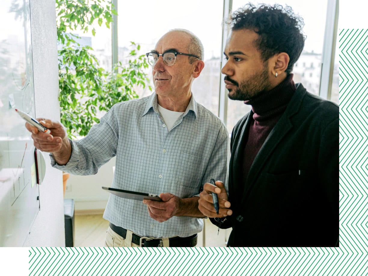 two men pointing at whiteboard